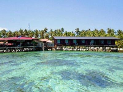 Clear waters by the shore and wooden resorts at Mabul Island