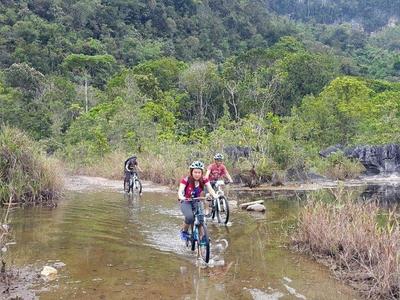 Cycling tourists crossing the shallow stream in countryside of Kuching