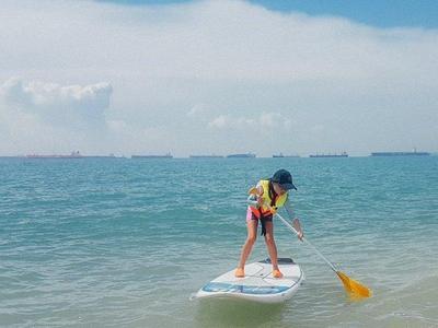 Kid learning how to stand up paddling in the ocean