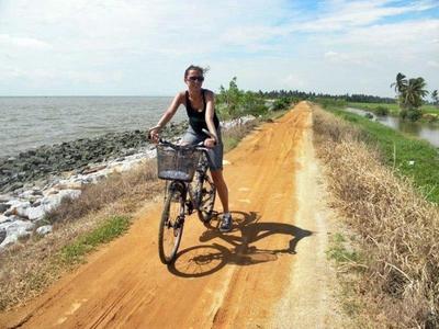 Lady cycling next to the ocean in Kerian