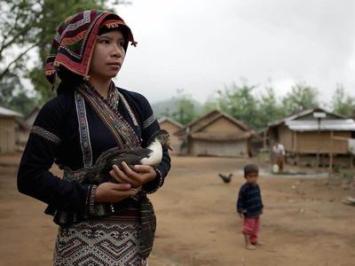 Lady holding a bird in her arm at a village in Nong Khiaw