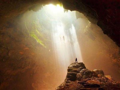 Man standing on top of a rock in Jomblang Cave