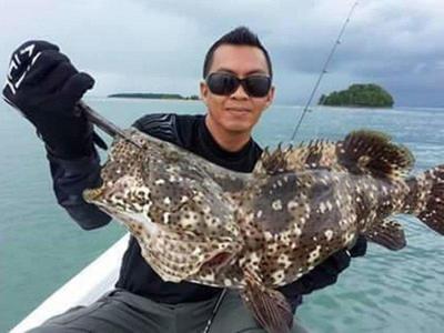 Man takes a picture with a grouper he caught in Langkawi