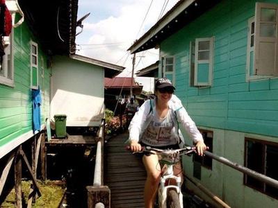 Tourist cycling through narrow boardwalks in Kuching city