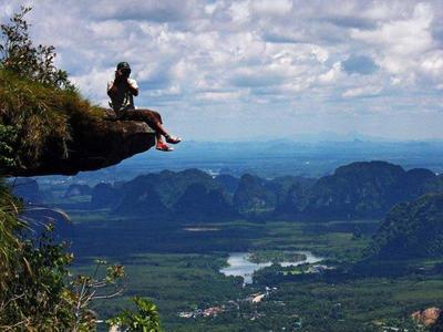 Tourist sitting on the edge of a rock hanging at Hang Nak National Park