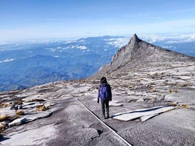 Tourist standing near the peak at Mount Kinabalu