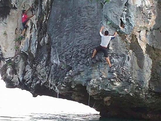 Tourists climbing up a rock sea cliff in Langkawi
