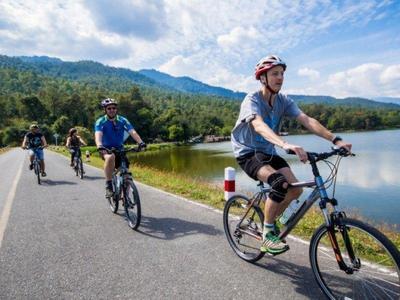 Tourists cycling past a lake at countryside of Chiang Mai
