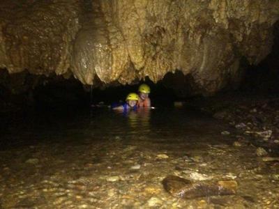Tourists exploring the cave crossing through pools of water inside Tempurung Cave