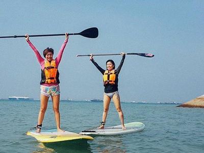 Tourists posing on top of a paddle board at Coney Island
